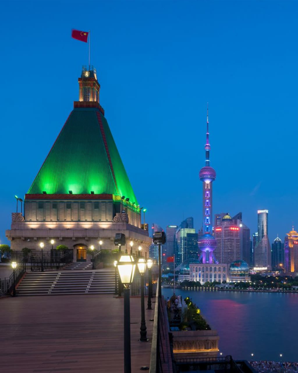 和平饭店铜绿色金字塔屋顶夜景，与黄浦江对岸东方明珠塔遥相呼应